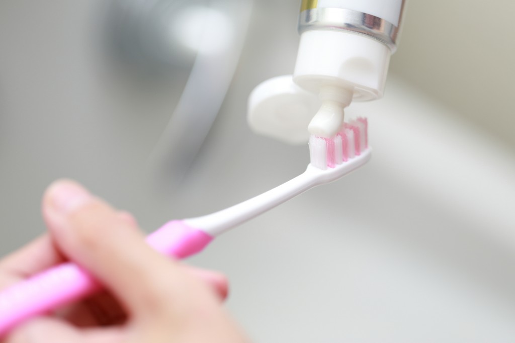 三好歯科 自由が丘歯のホームケア ピンクの歯ブラシに歯磨き粉をつける画像